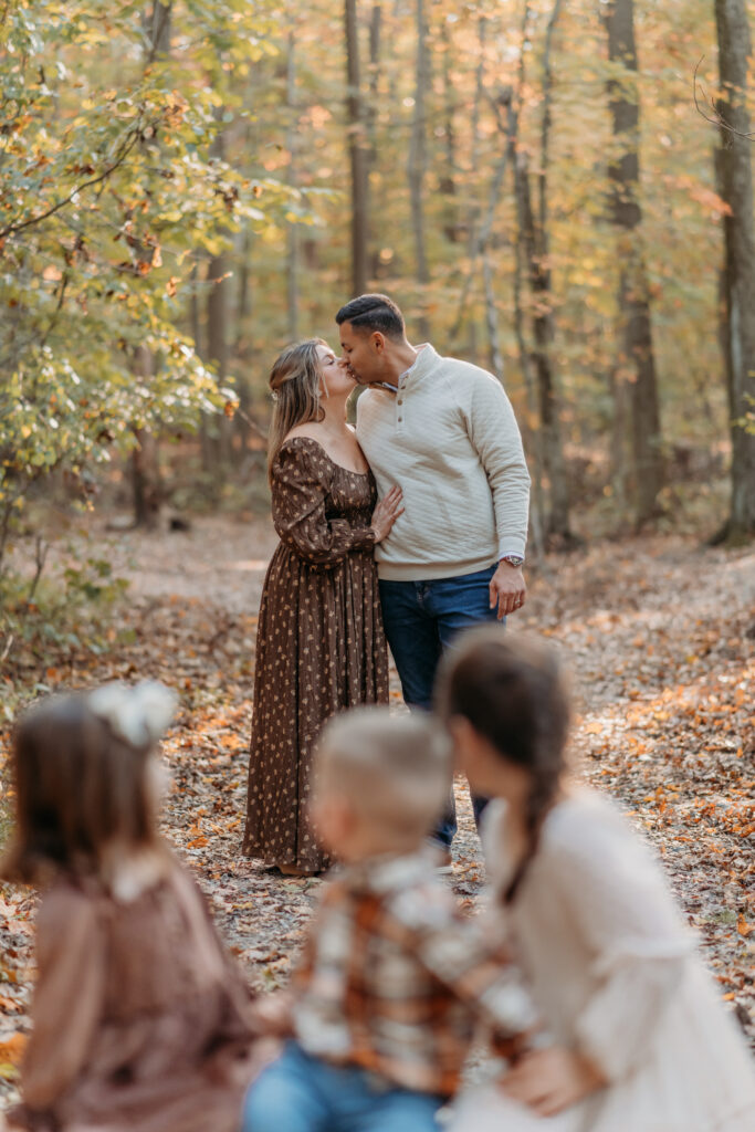 kids watching mom and dad kiss in fall family photos